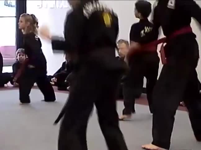 A vintage clip shows a mixed-age group of Kuk Sool Won students practicing synchronized kicks and stances in a dojo