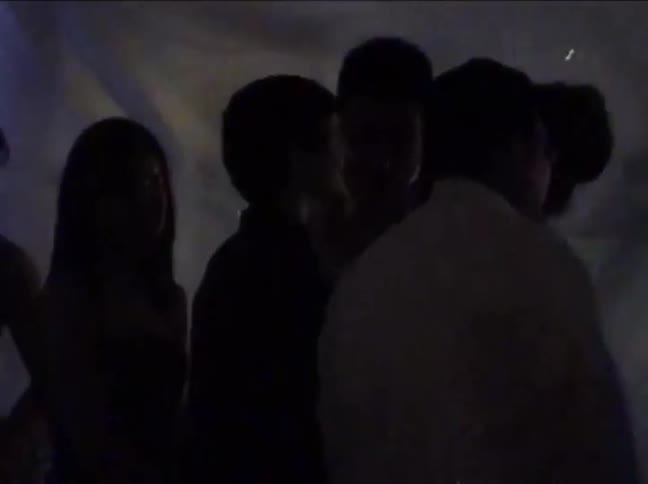 Grainy, vintage home video footage captures silhouetted couples slow dancing at a party in the 1990s