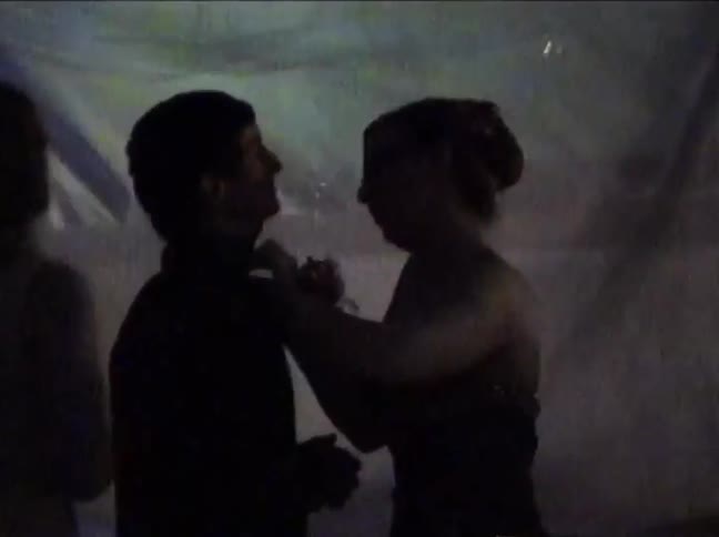 A slow zoom on a silhouetted couple kissing at a party with vintage lighting in this home movie footage
