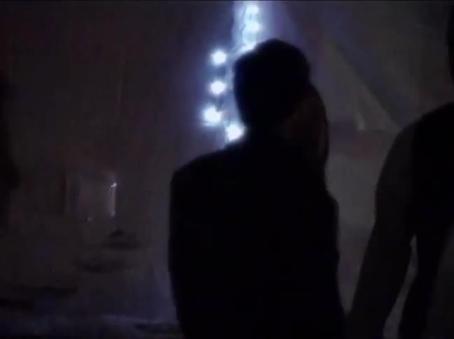 Vintage VHS footage captures the silhouettes of young people socializing and slow dancing at a dimly lit party