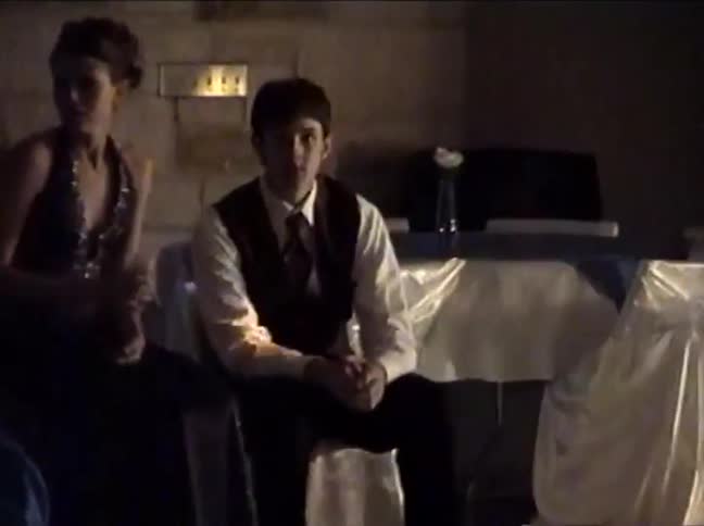 Authentic 90s home video footage from a school dance slowly zooms in on an awkward young man sitting on the sidelines before he notices the camera and smiles