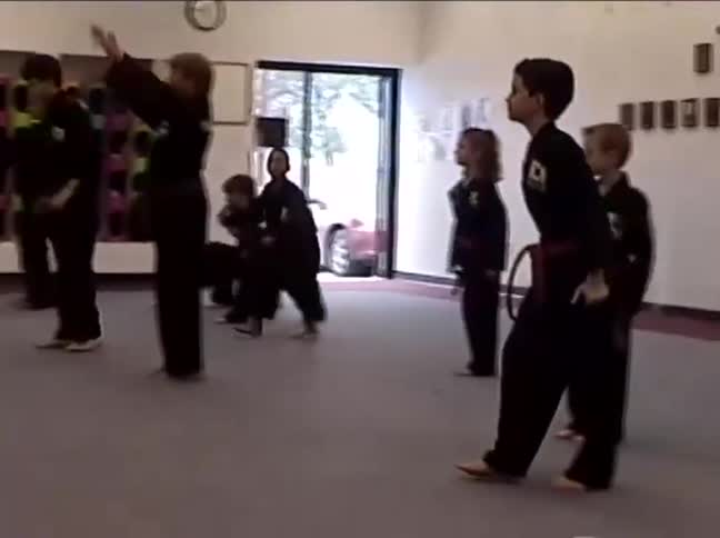 Vintage footage of a children's martial arts class performing a synchronized kata routine in a dojo