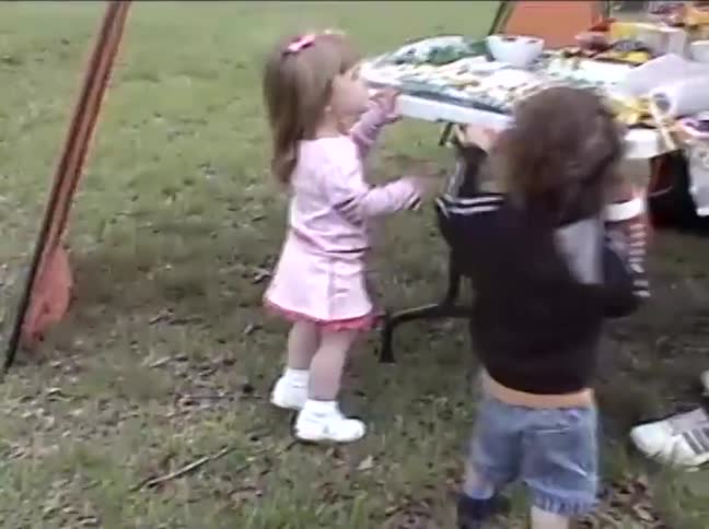 Vintage home video of a toddler boy holding a football at a family picnic in a park