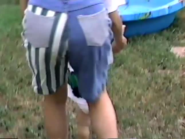 Vintage VHS home video footage of a parent helping a baby learn to walk in the backyard