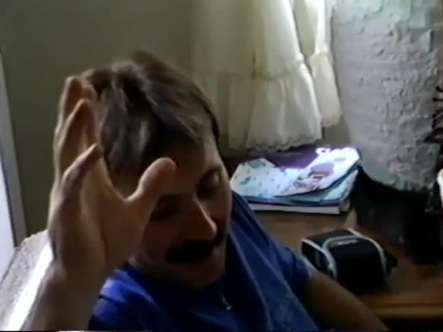 A man with an 80s-style mullet and mustache comically rolls his eyes back and pretends to faint for the camera