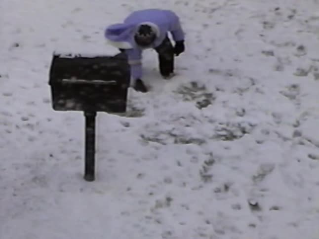 A nostalgic home movie captures two children playing and shoveling snow in their backyard on a winter day