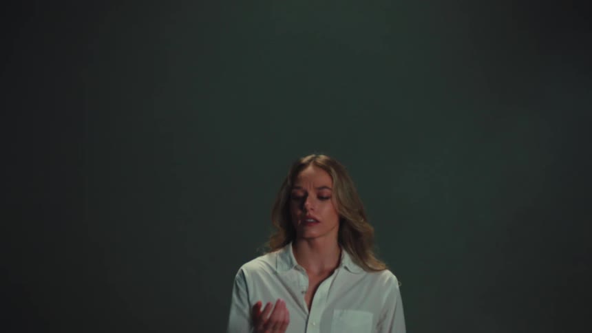 A concerned woman watches a piece of paper labeled 'bad' fall slowly from the sky in a dramatic studio setting