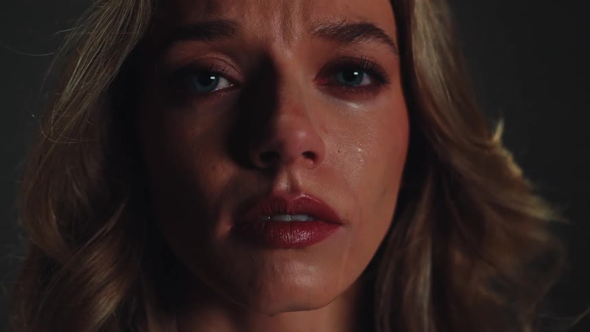 An emotional close-up of a sad woman with tears in her eyes as she slowly looks into the camera
