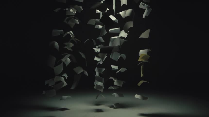 Numerous sheets of paper fall gracefully in slow motion under a single spotlight against a dark background