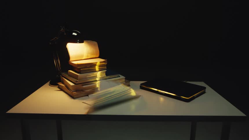 Dramatic shot of a desk in a dark room where the wind blows the pages of books and papers with a glowing waveform projected on them