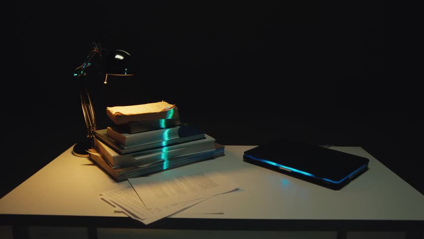 A glowing green audio waveform animates on a stack of books sitting on a dimly lit desk