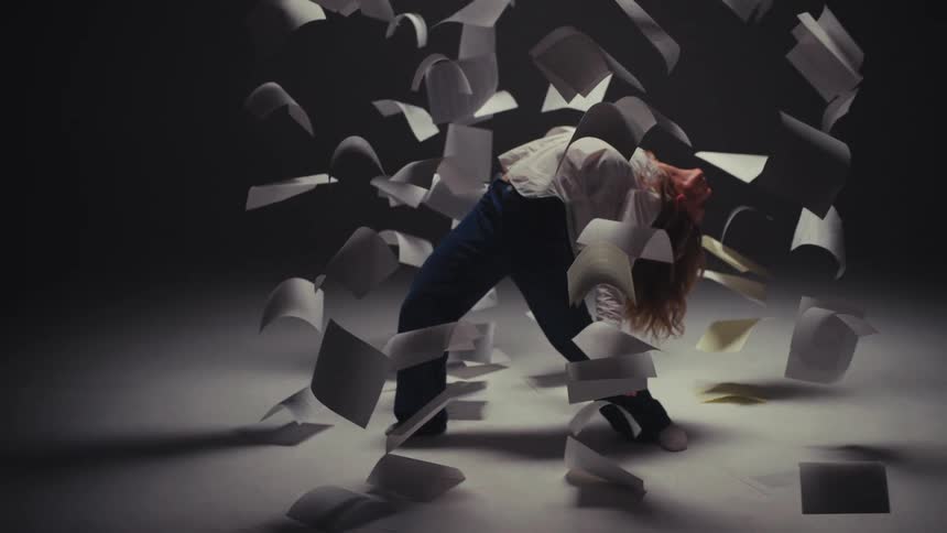 A woman gracefully falls backward in super slow motion, suspended in time amidst a storm of floating white paper