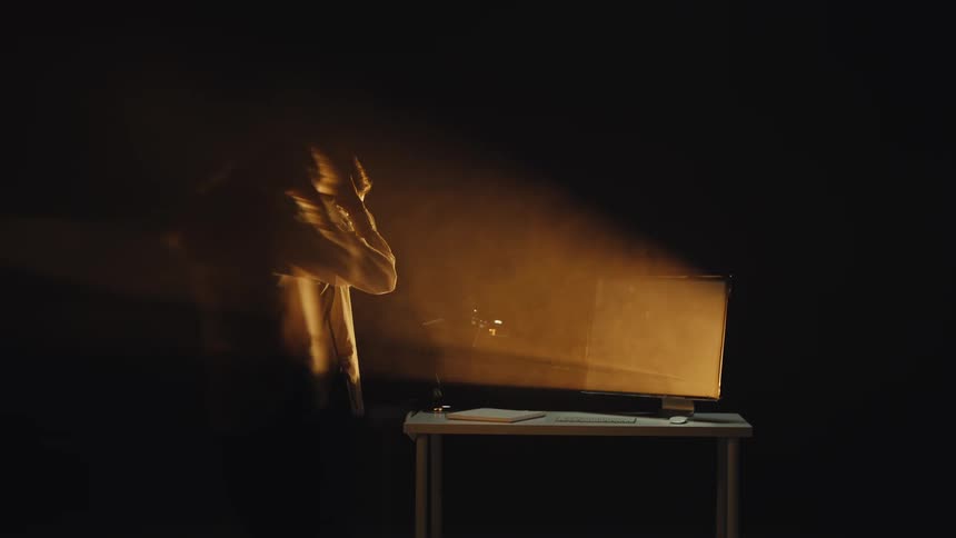 A long exposure captures the ghostly movements of a female podcaster or singer as she records audio in a dark, hazy room