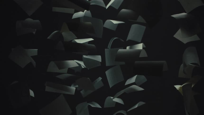 Abstract shot of curled paper sheets floating slowly in the darkness