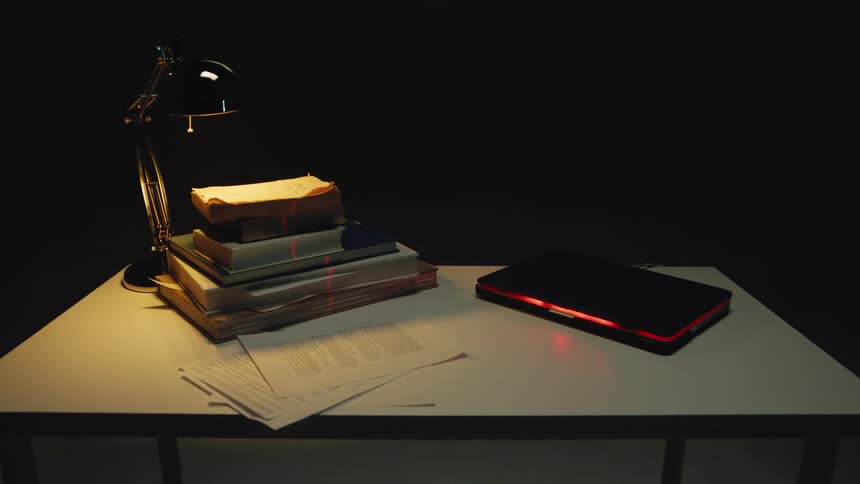 In a dark room, a laser scanner analyzes top-secret information from old books and a modern laptop on a desk