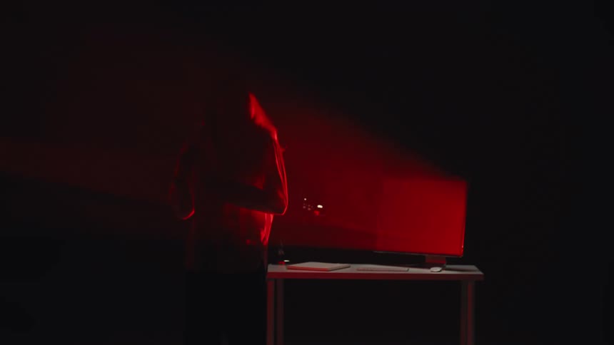 An emotional artist passionately sings into a microphone in a dark, smoky recording studio with dramatic red lighting