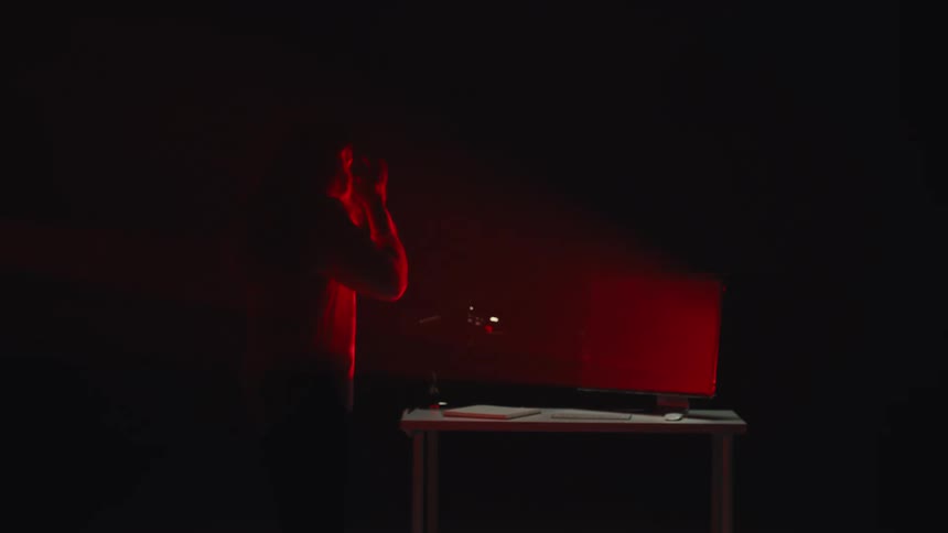 A passionate singer records a vocal track, her silhouette illuminated by a dramatic red light in a dark recording studio