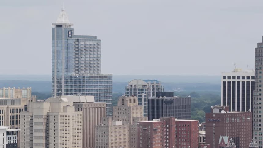 An aerial telephoto view slowly pans across the downtown Raleigh, North Carolina skyline on an overcast day
