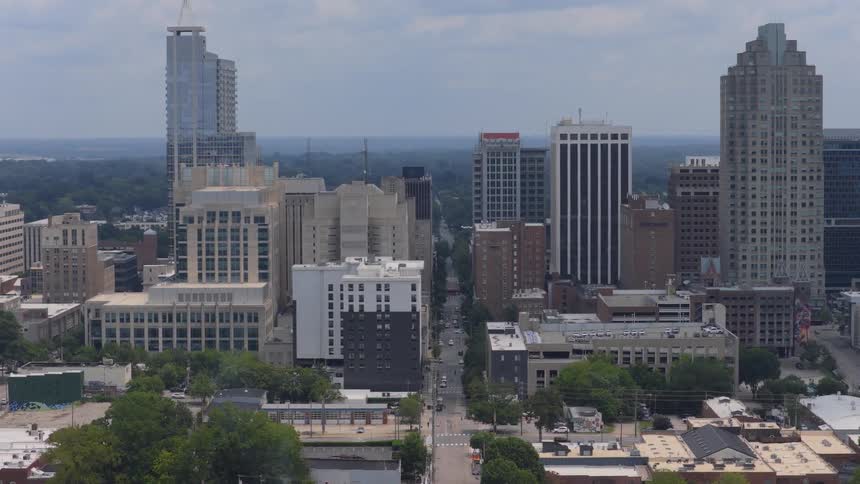 Aerial pullback shot revealing the downtown city skyline and streets of Raleigh, North Carolina on a cloudy day