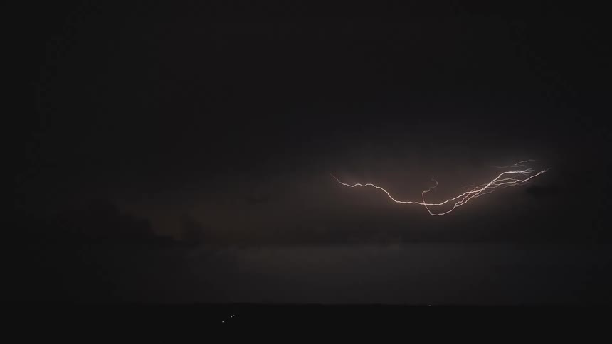 A powerful lightning strike illuminates the dark, stormy night sky in a dramatic display of nature's force