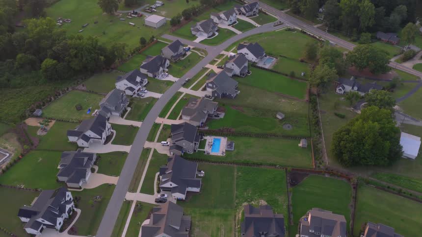Ascending aerial footage captures a tranquil modern suburban neighborhood with large homes and manicured green lawns