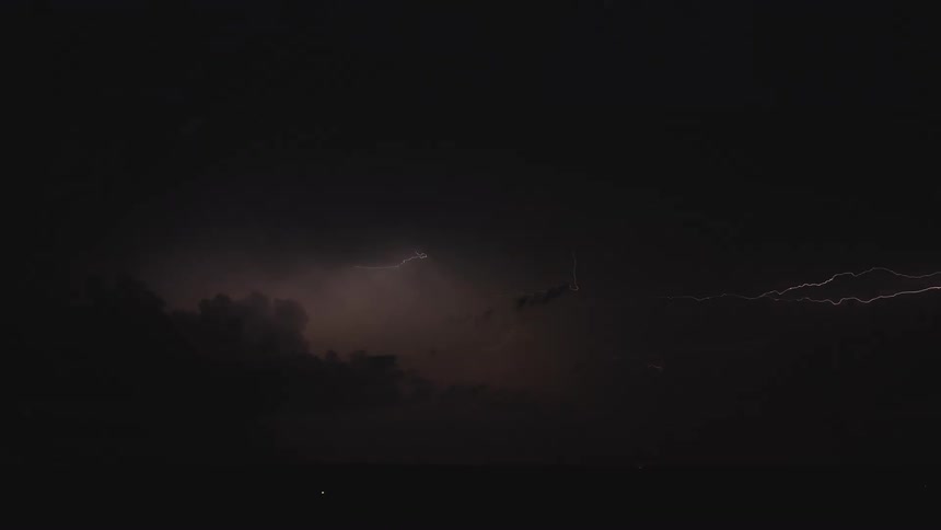 A dramatic lightning strike flashes across the dark clouds in the night sky