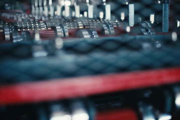 A slow-motion close-up of an industrial machine with rotating metal rollers on a production line