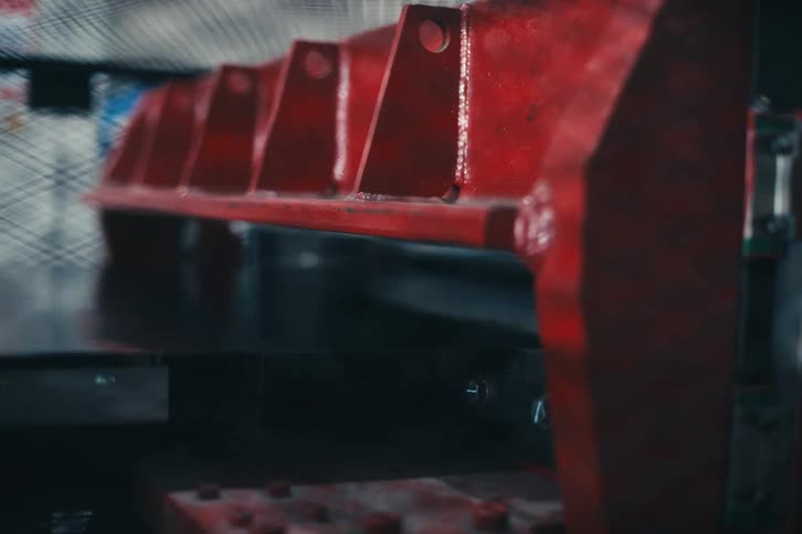 Close-up of a large red industrial press machine operating automatically in a metalworking factory