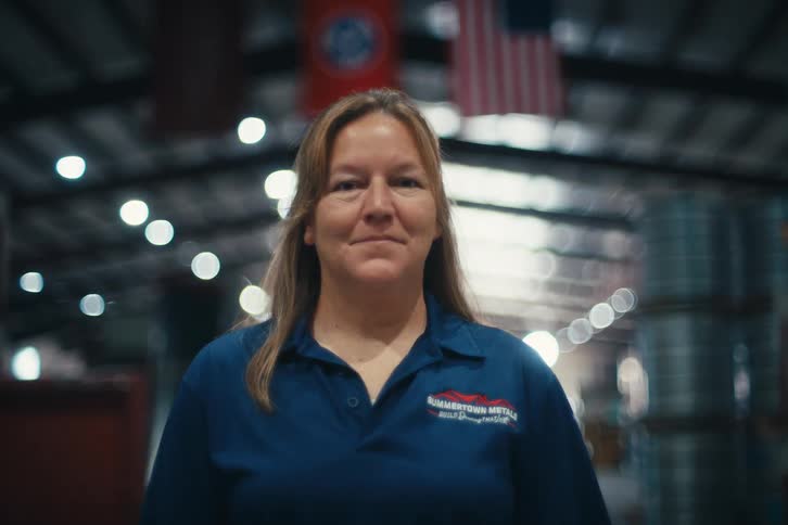 Portrait of a proud female factory worker standing in a large American manufacturing warehouse