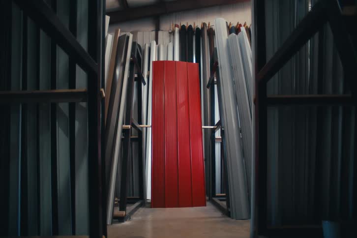 Vibrant red corrugated metal panels stand out against neutral-colored panels in a symmetrically framed warehouse shot