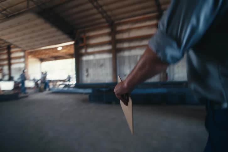 Slow motion following shot of a factory worker walking through a metal fabrication workshop
