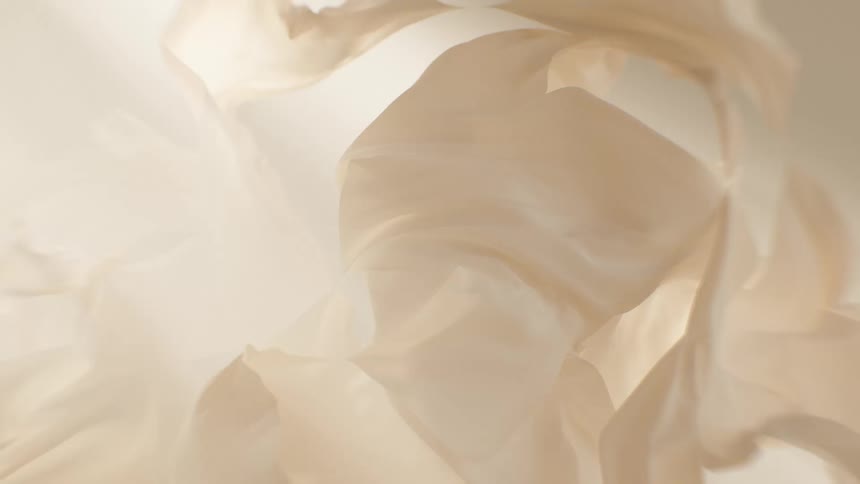 Ethereal and dreamy beige silk fabric flows gently in slow motion against a soft background