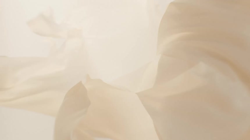 Delicate, sheer beige fabric flows gracefully in a dreamy slow-motion abstract background