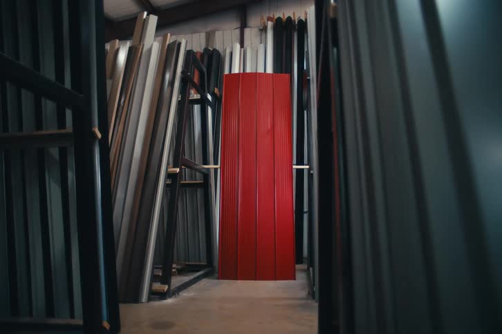 Slow dolly shot of bright red corrugated metal panels standing out in an industrial warehouse