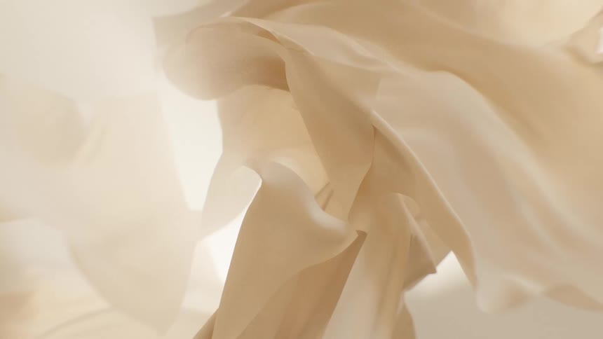 A close-up of sheer, cream-colored fabric moving gracefully in slow motion