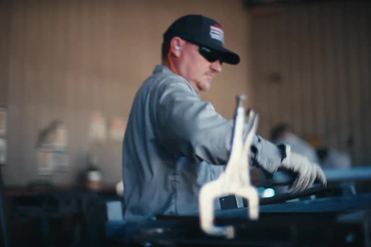 A rack focus shot in a metal workshop reveals workers assembling steel frames for manufacturing