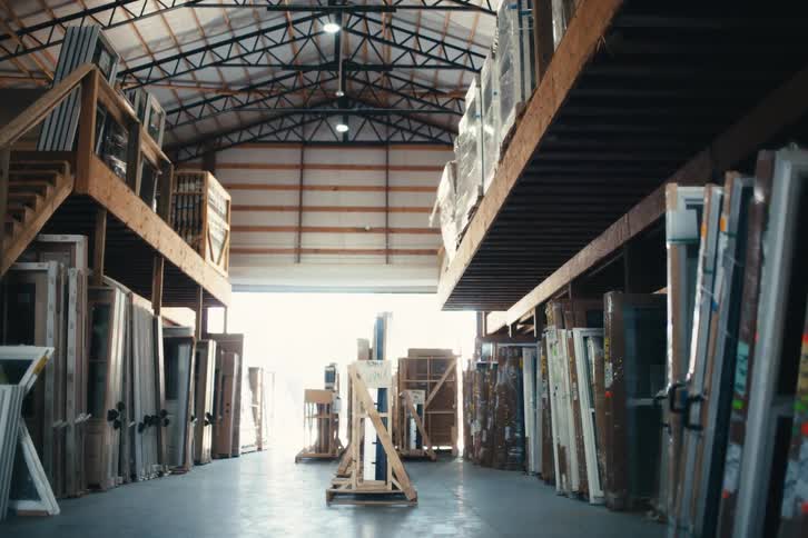 A slow downward tilt reveals an industrial warehouse full of doors and windows ready for shipment