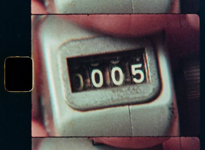 A macro shot on vintage film of a hand clicking a mechanical tally counter from zero to ten