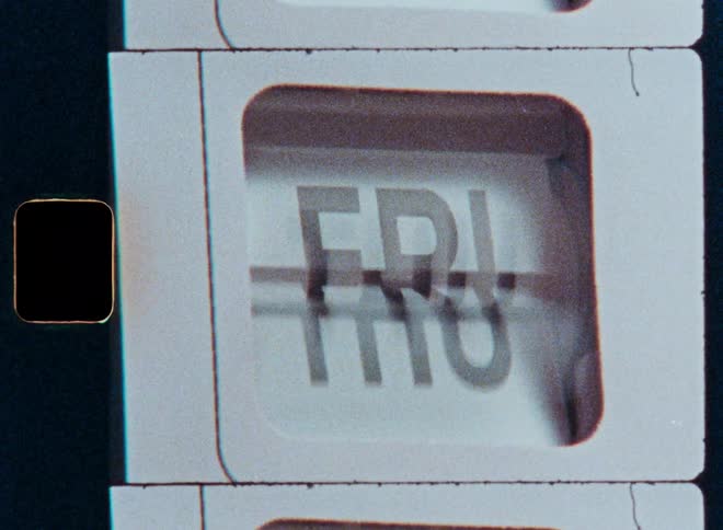 A vintage flip calendar quickly cycles through the days of the week in a close-up shot on grainy film