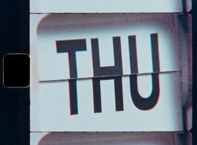 A vintage flip calendar with film sprockets on the side cycles through the days of the week in a grainy, retro film style