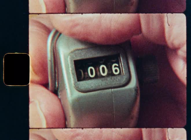 A vintage mechanical tally counter is used to count up from zero in a retro film close-up
