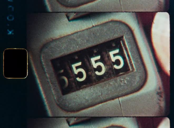Close-up retro 8mm film footage of a mechanical tally counter being reset as the numbers cycle backwards