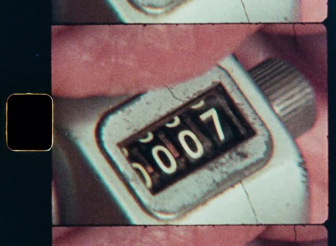 A vintage film scan shows a close-up of a hand clicking an old mechanical tally counter as the numbers increase