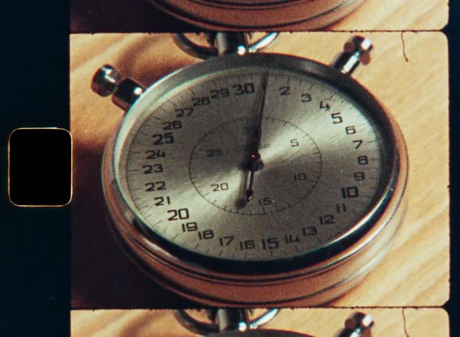 A close up shot of a vintage stopwatch with the seconds hand ticking on a wooden table, shot on 16mm film