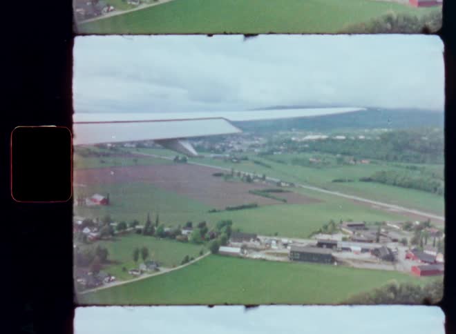 Authentic vintage footage from an airplane window shows the wing gliding over a lush, green landscape