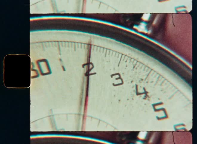A vintage 8mm film strip shows a close-up of a ticking stopwatch as seconds pass