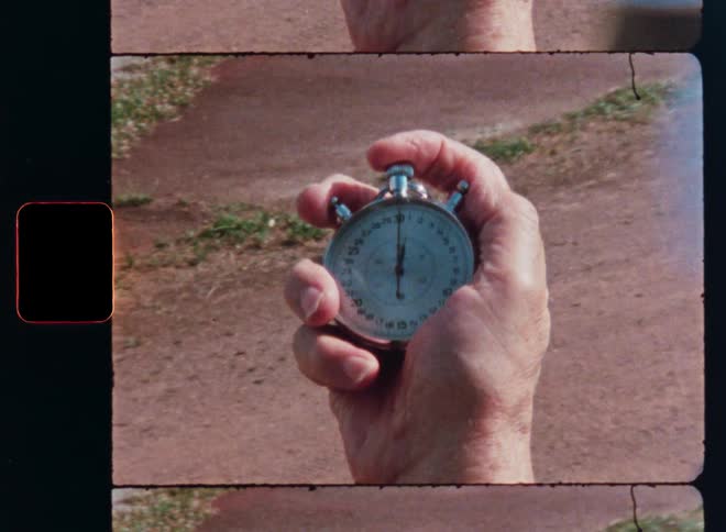 A close-up shot of a hand holding a vintage analog stopwatch as a finger presses the button to stop the time