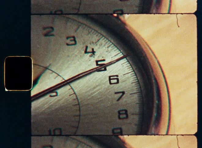 A vintage Super 8 film scan shows an extreme close-up of a stopwatch as its second hand ticks