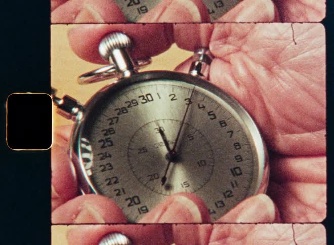 A close-up of a classic analog stopwatch counting seconds while being held, with a retro film strip effect