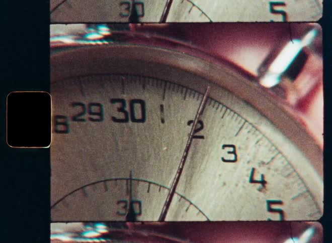 Close-up of a vintage analog stopwatch with the second hand ticking, presented as a classic film strip